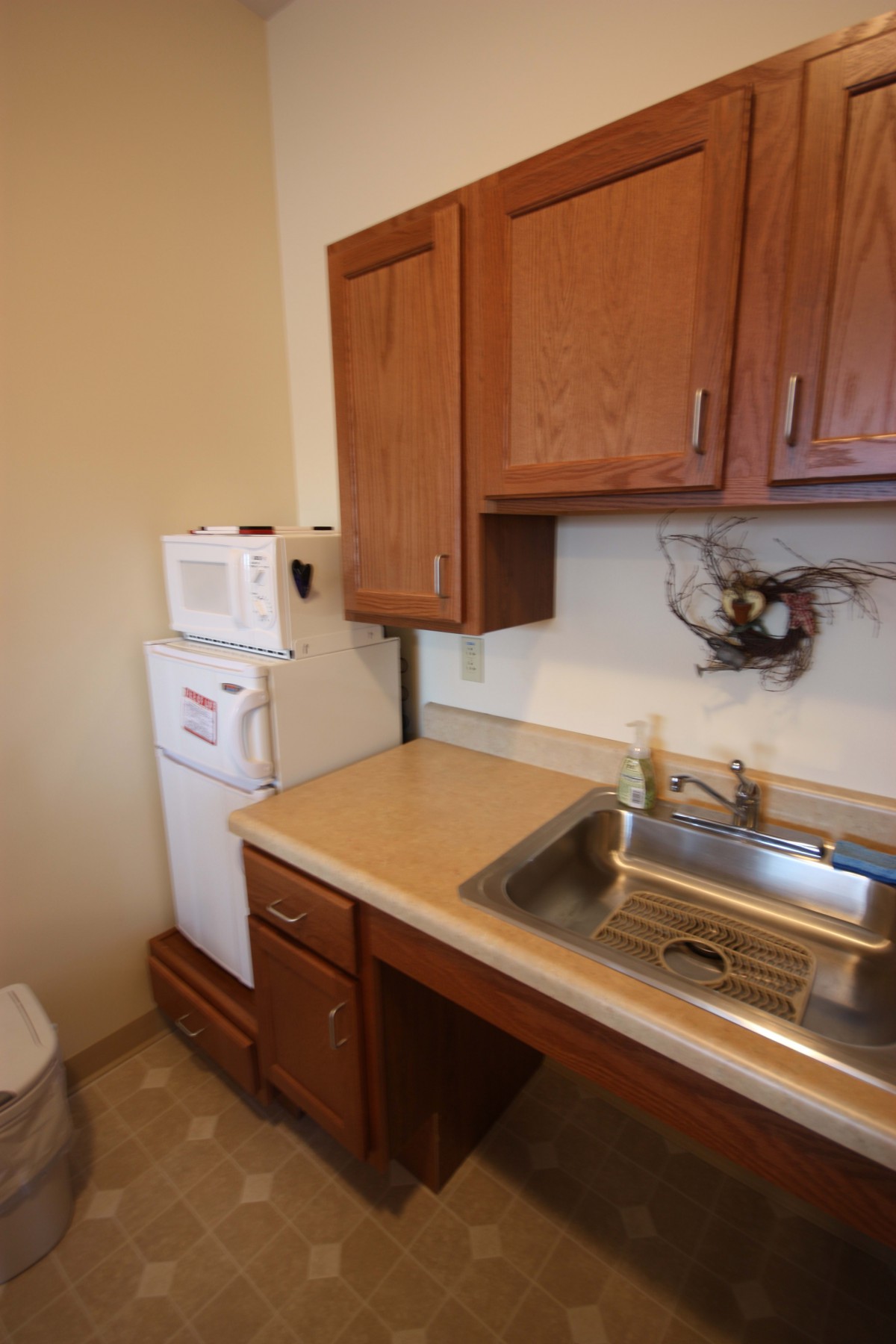 A small kitchen with wooden cabinets, a sink, and appliances including a microwave and fridge.