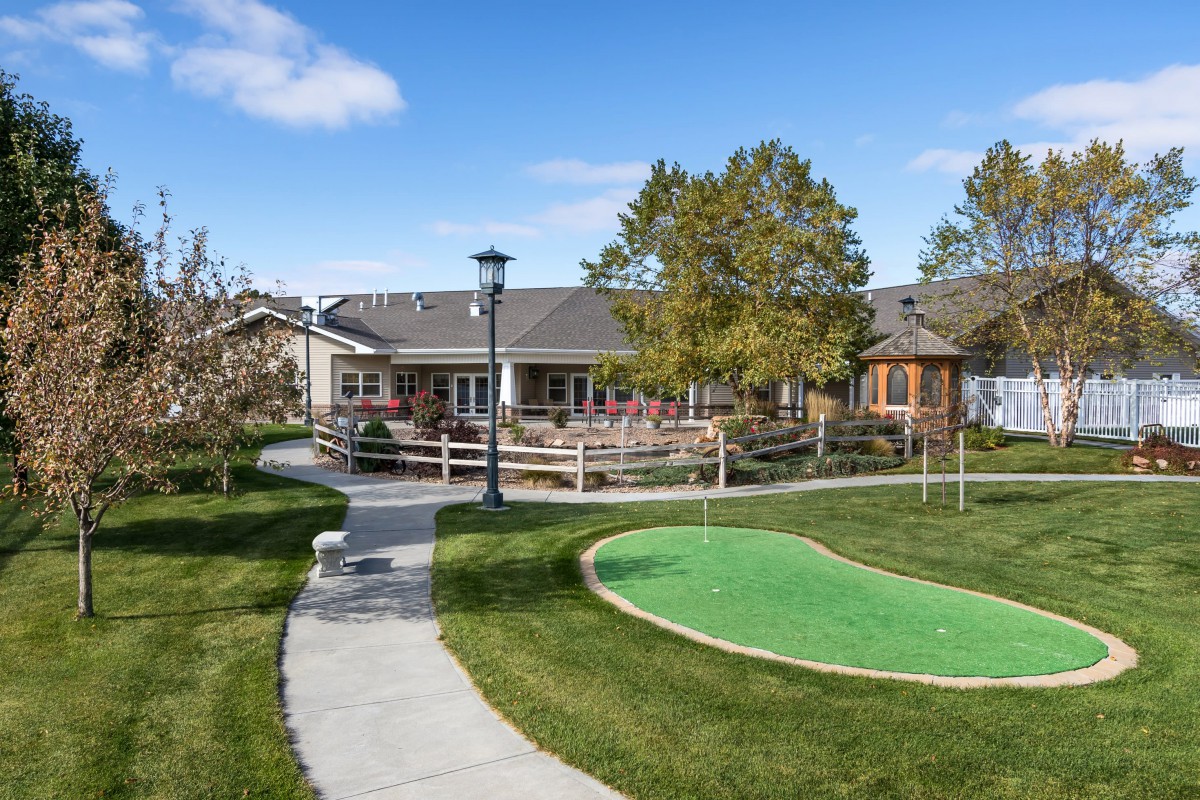 A well-maintained backyard with a house, pathway, and lush green lawn.