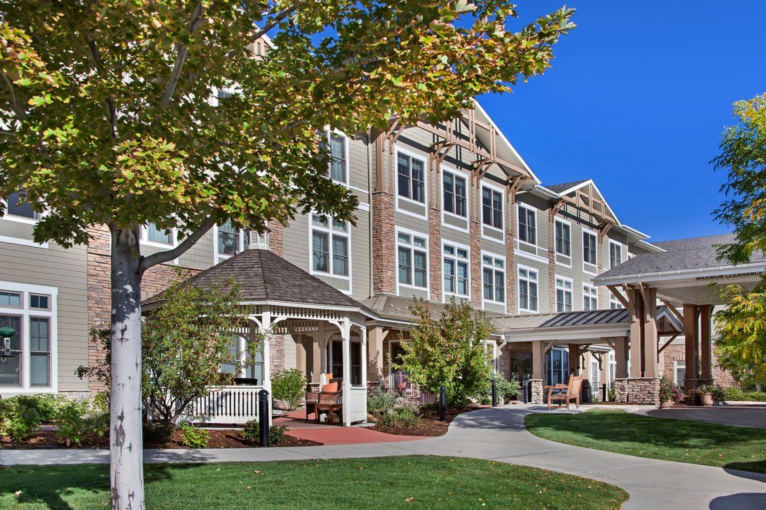 A picturesque residential building surrounded by a well-maintained landscape and trees under a clear blue sky.