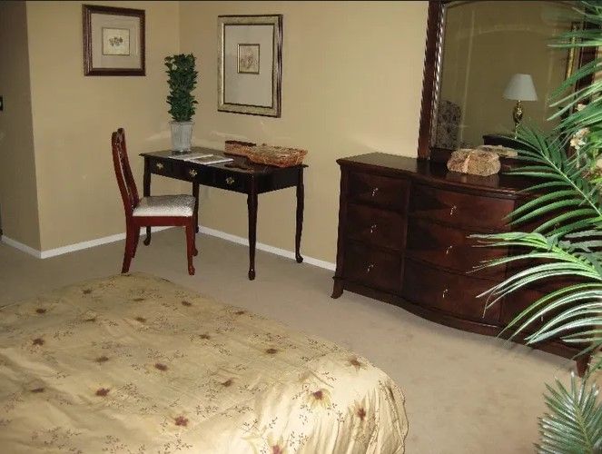 A cozy bedroom with a desk, chair, and dresser.