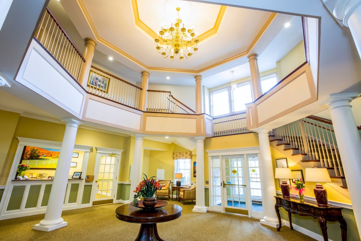 A spacious and elegant lobby with a grand staircase and chandelier, filled with natural light.