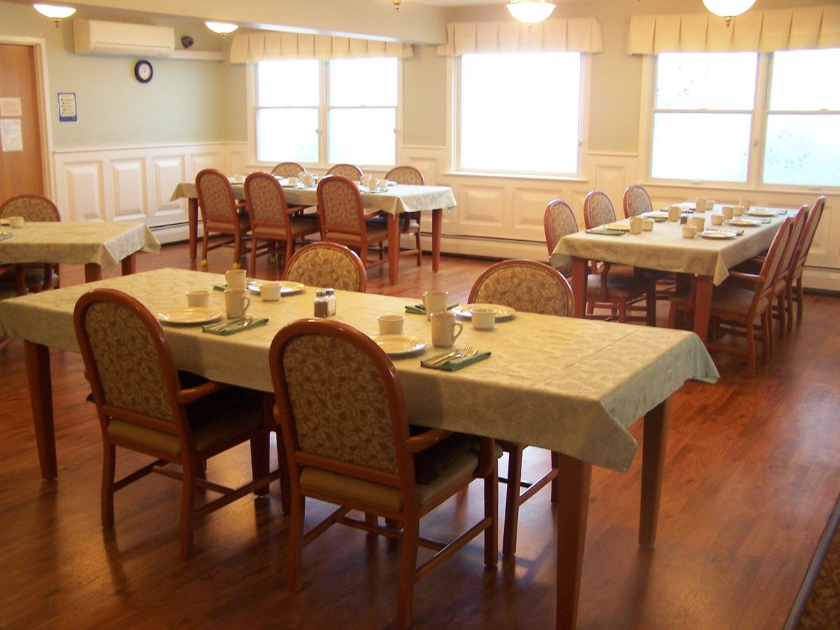 A neatly arranged dining room with tables set and chairs placed around them.