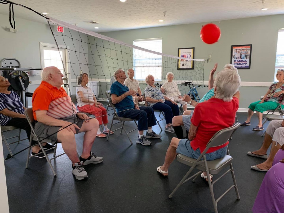 A group of seniors participating in a fun ball exercise at a community center.