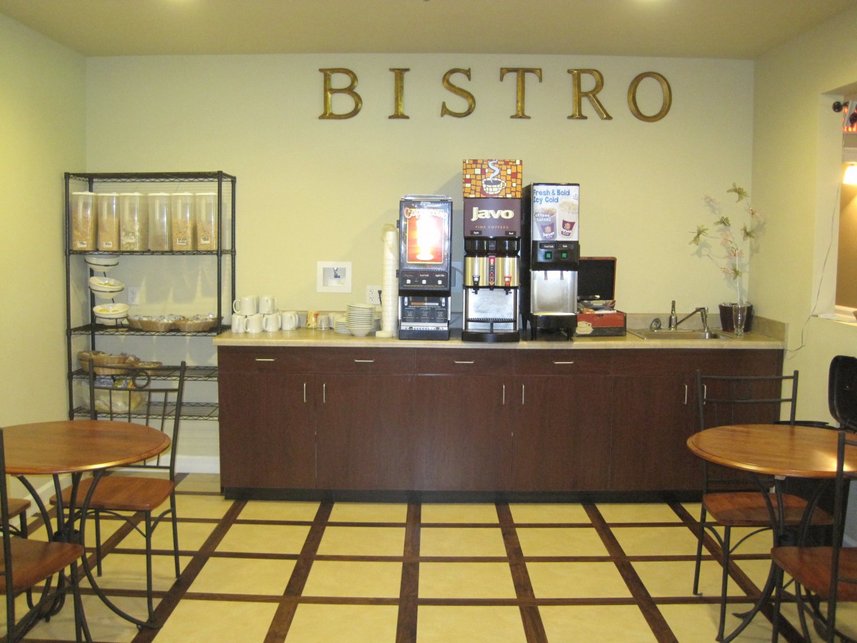 Interior of a bistro featuring a coffee station with beverage dispensers and seating area.