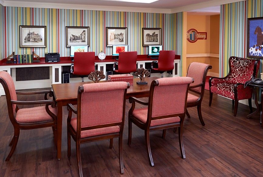 A well-decorated conference room featuring a large wooden table, upholstered chairs, and framed artwork on the walls.