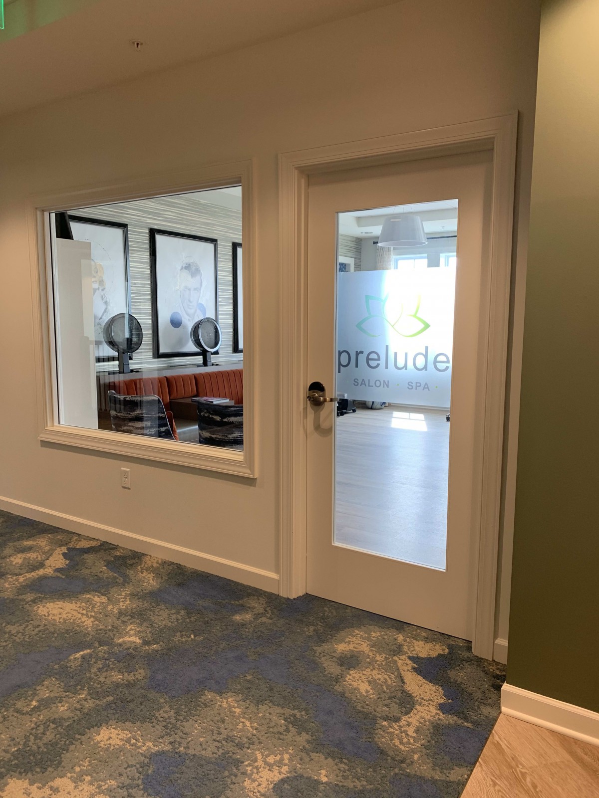 A view of a modern office space with a glass door and interior window.