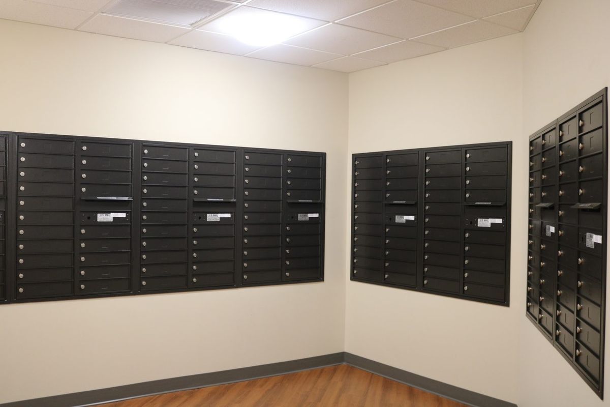 An indoor mail room with rows of black mailboxes mounted on the walls.