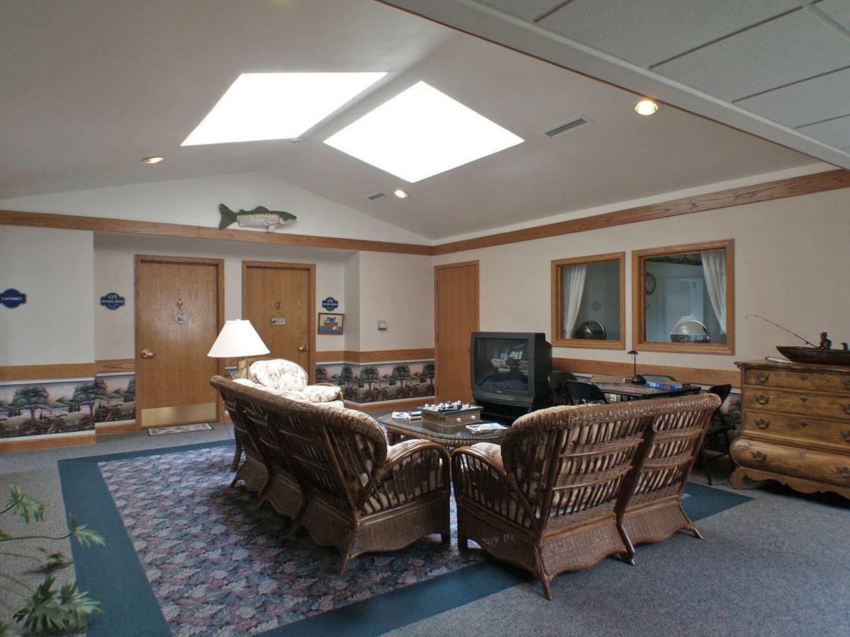 A cozy living room with wicker furniture, a TV, and natural light from skylights.