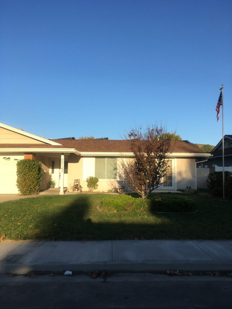 A suburban house with a front yard and a flagpole under a clear blue sky.