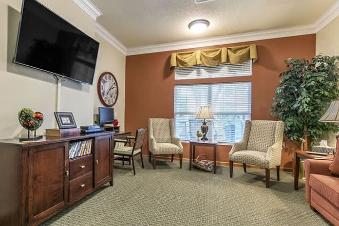 A cozy living room with a television, chairs, and decorative elements.