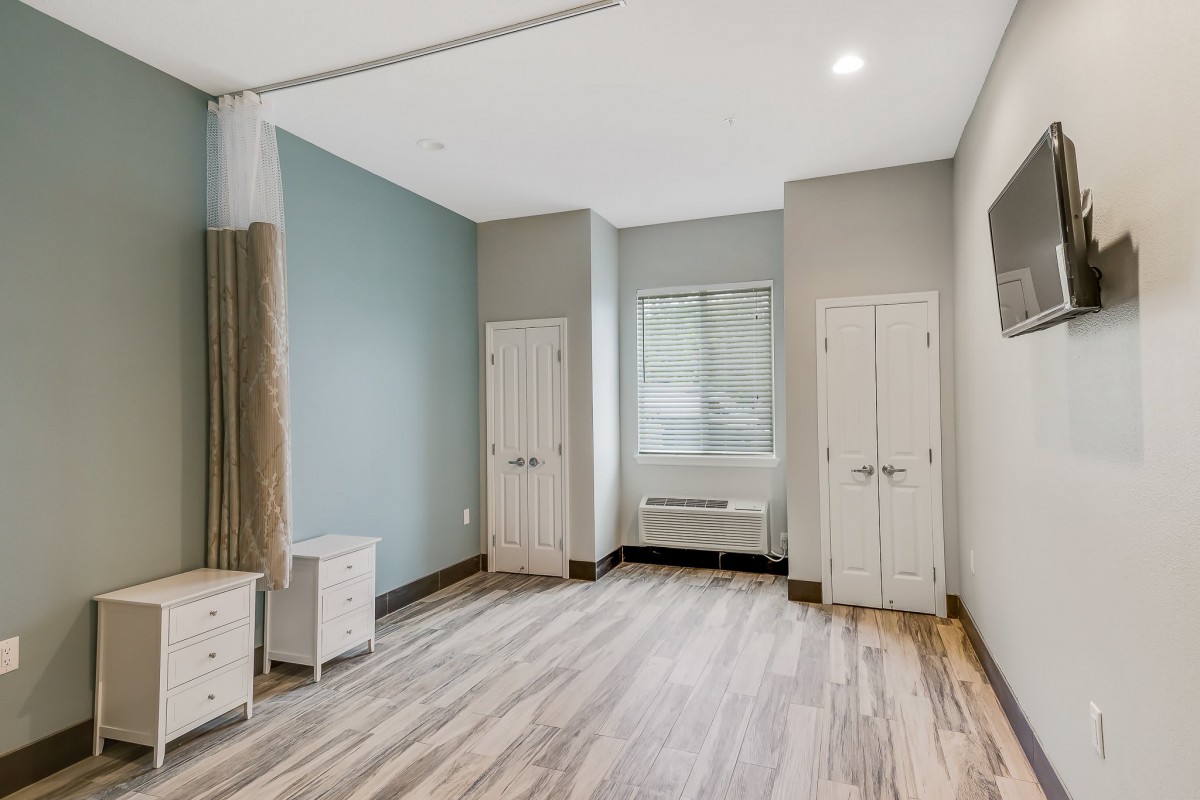 A modern, empty room with wooden flooring and natural light.