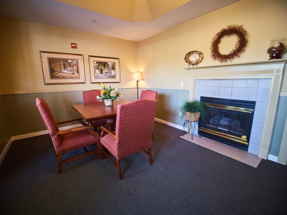 Cozy living room with a dining set and fireplace, decorated with artwork and a wreath.