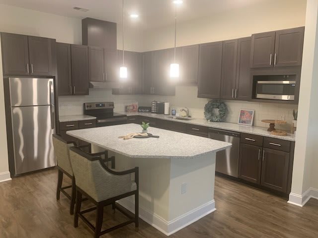 A modern kitchen featuring an island with seating, stainless steel appliances, and sleek cabinets.