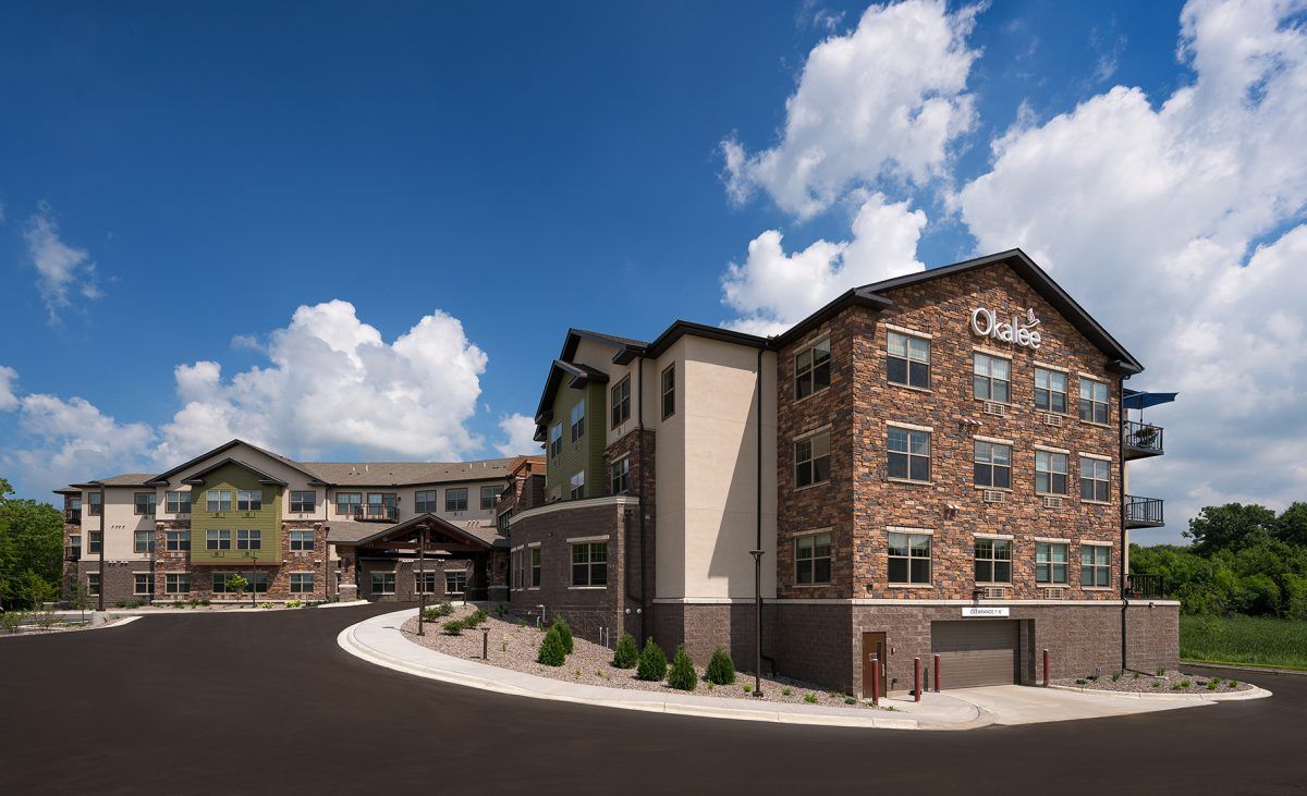 A modern apartment complex with a stone facade under a partly cloudy sky.