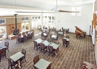 A spacious indoor dining area with multiple tables and a piano.