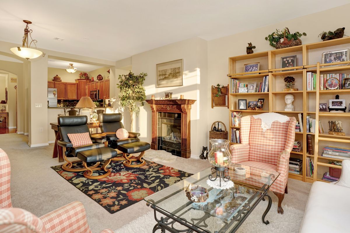 A cozy living room featuring comfortable seating, a fireplace, and well-arranged bookshelves.