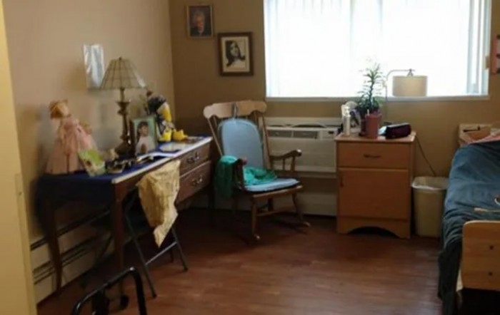 A cozy room with a rocking chair, dresser, and window letting in natural light.