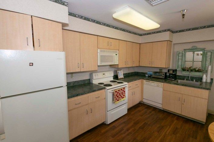 A clean and organized kitchen featuring wooden cabinets, a stove, microwave, refrigerator, and dishwasher.