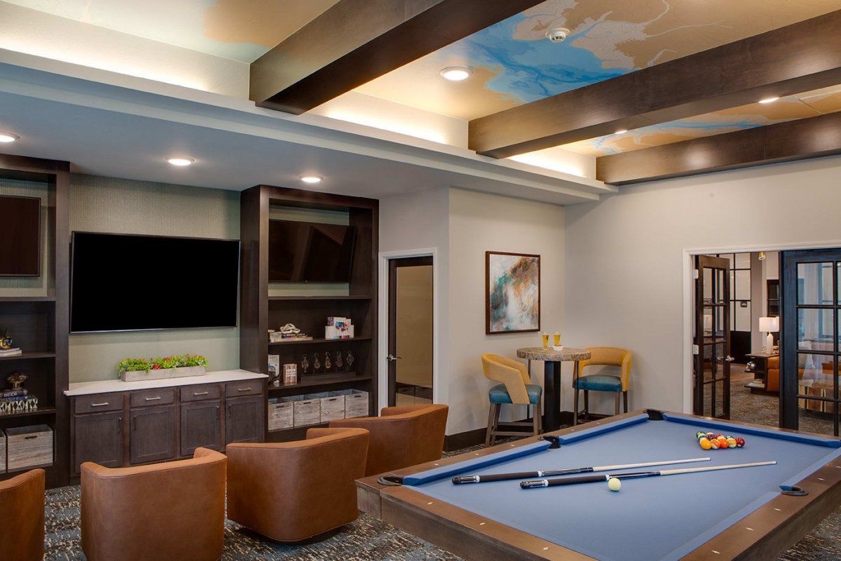 A modern game room with a pool table, cozy seating, and a large television for entertainment.
