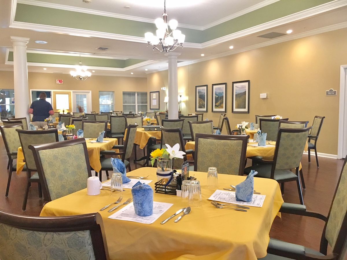 A spacious dining room with neatly arranged tables and chairs, featuring elegant decor and table settings.