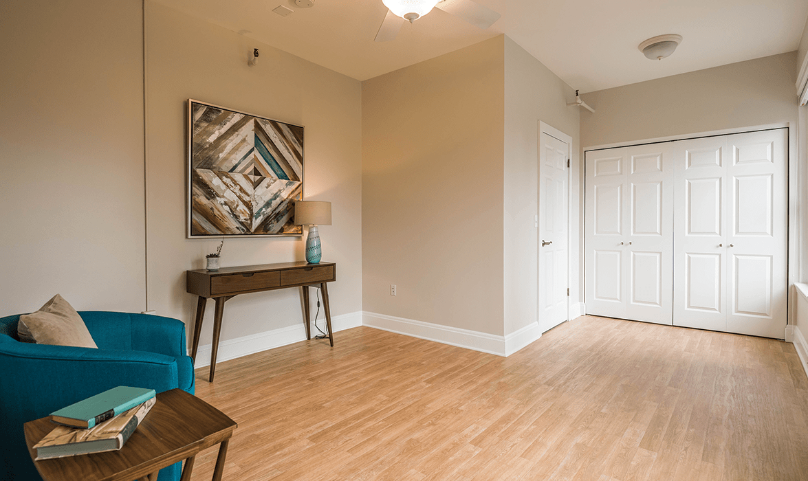 A modern living room with wood flooring, featuring a console table, contemporary artwork, and stylish lighting.