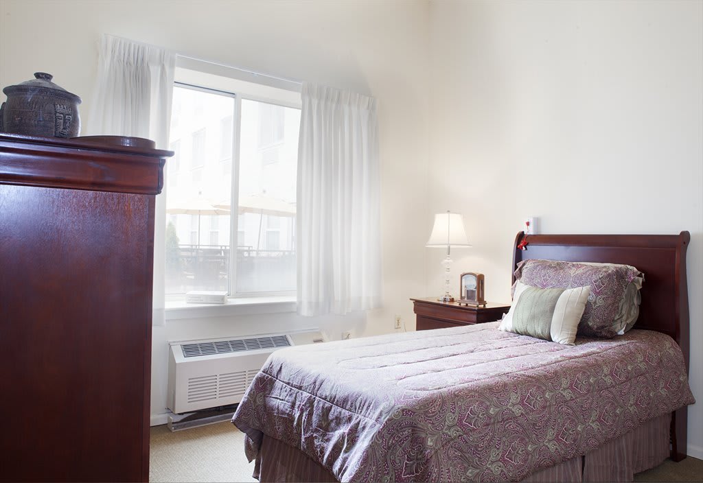 A cozy bedroom with a single bed and natural light coming through the window.