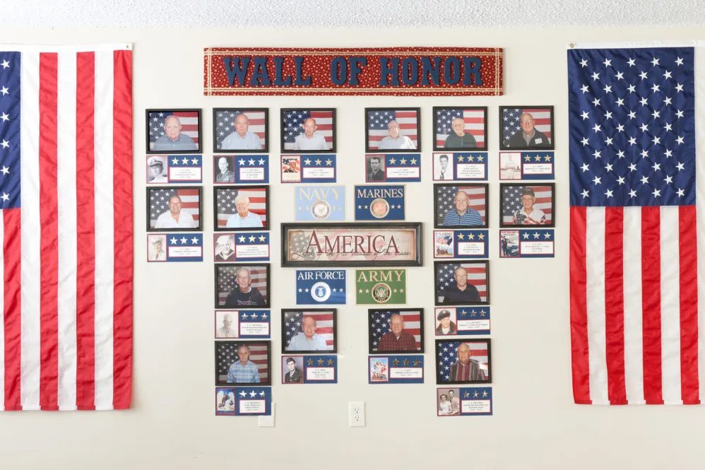 A tribute wall titled 'Wall of Honor' featuring photos and information about veterans, with American flag motifs prominently displayed.