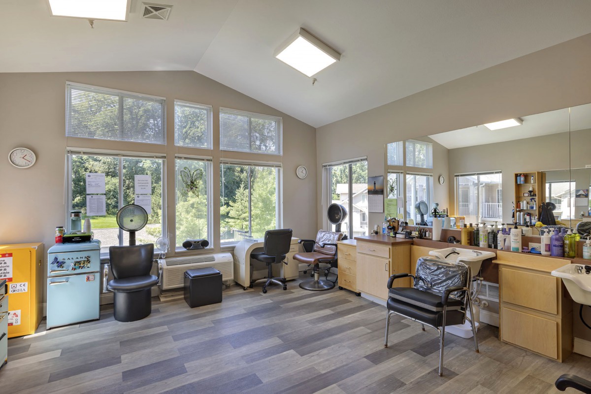 A modern hair salon interior with large windows and daylight streaming in.