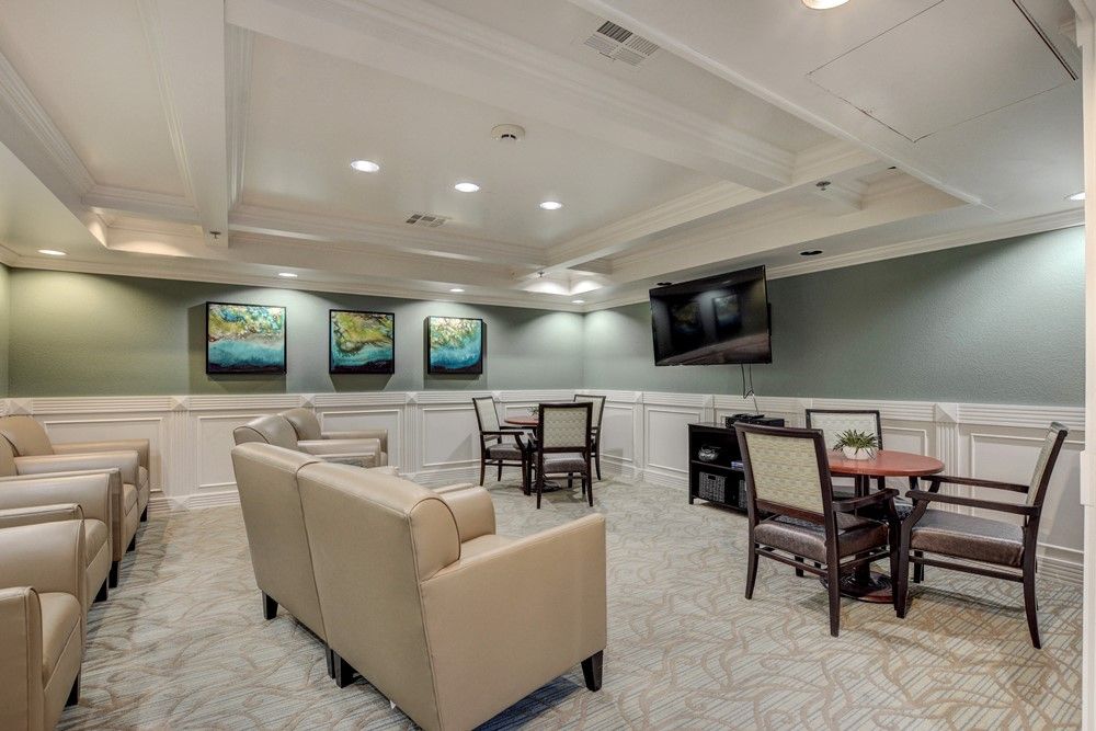 A modern lounge area featuring comfortable seating, tables and chairs, wall art, and a mounted TV.