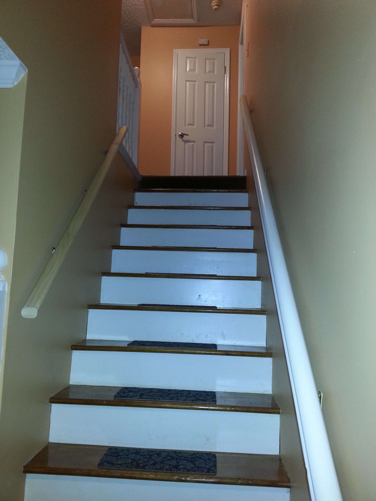 Staircase leading to a closed door at the top of a hallway.