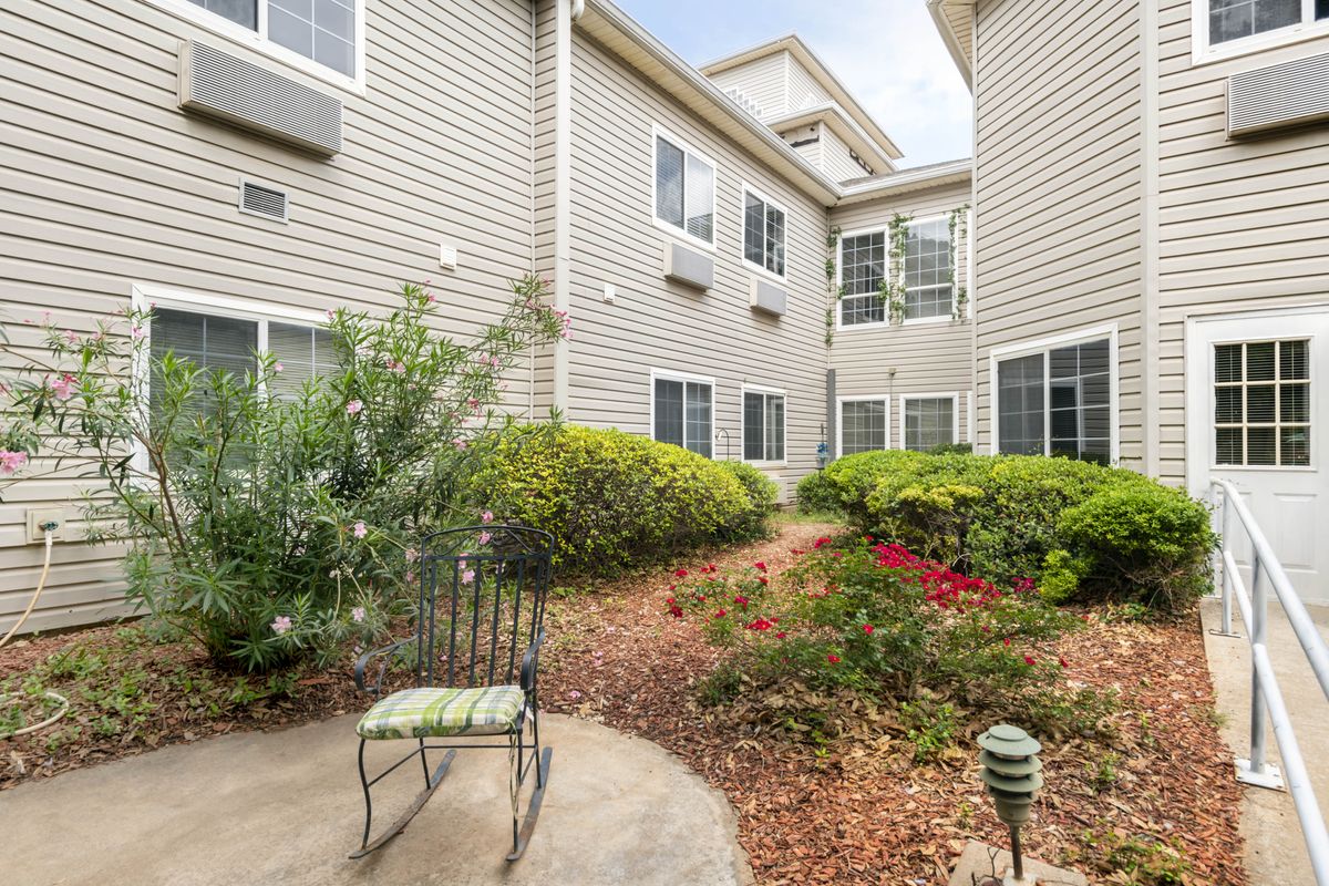 A tranquil courtyard with outdoor seating amidst lush greenery and an apartment building.