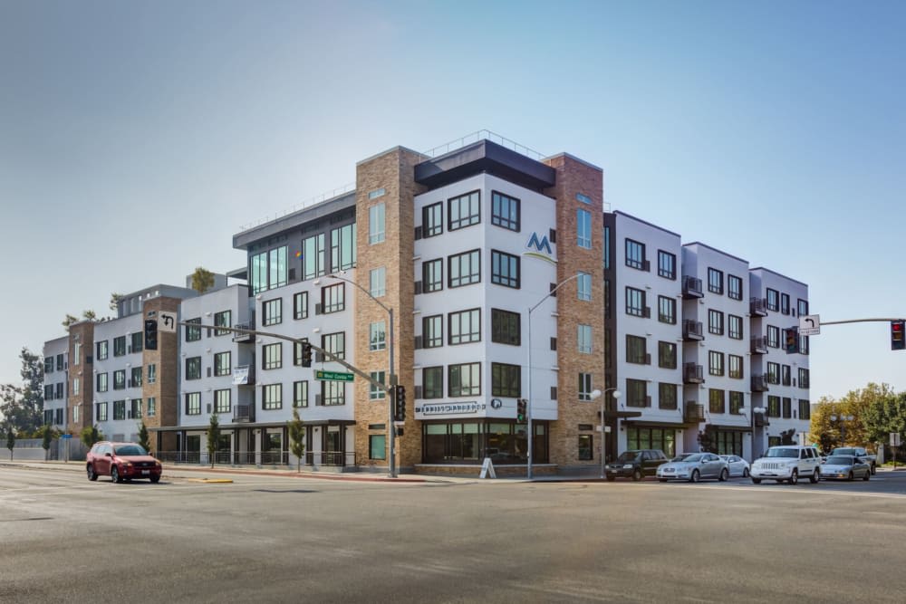A modern apartment building on a street corner in an urban setting.