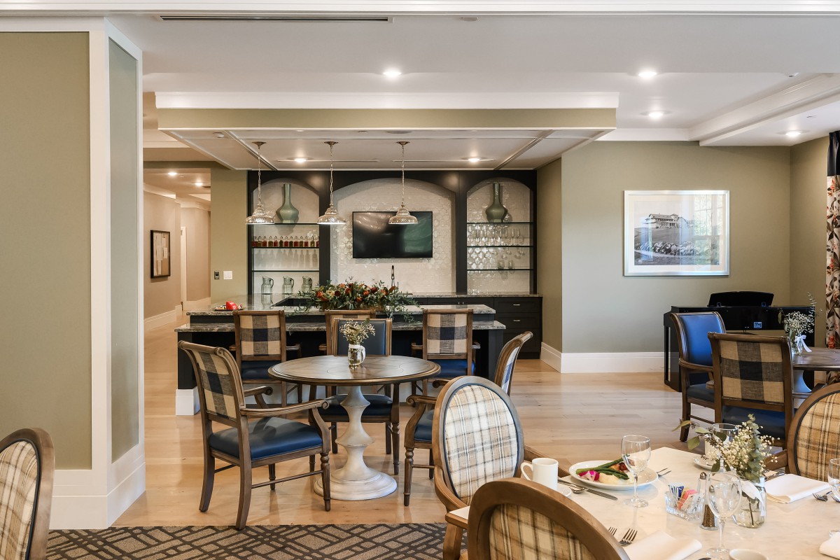 A stylish dining area featuring elegant furniture and a well-lit bar.