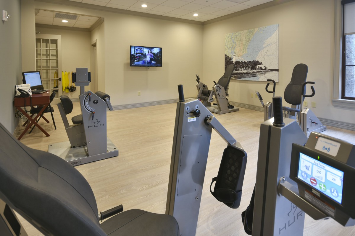 A modern gym with various exercise equipment and cardio machines.
