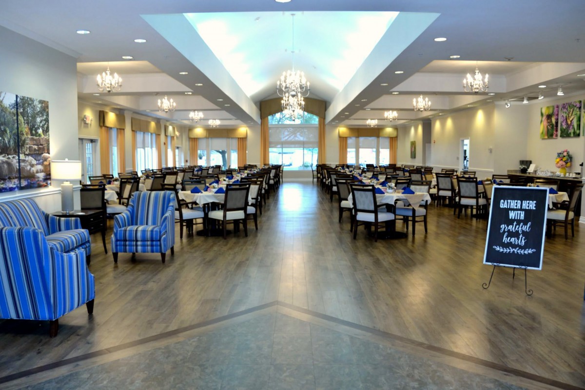 An elegant dining room with tables and chairs arranged symmetrically under chandeliers.