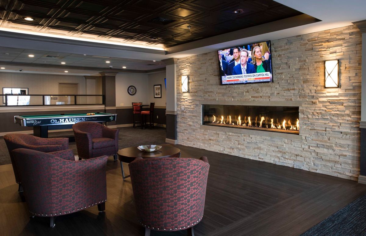 A modern lobby area with comfortable seating, a linear fireplace, and a television.