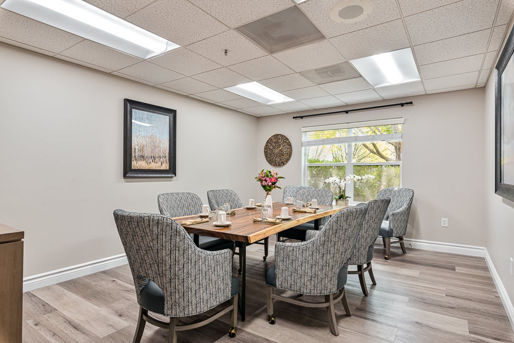 A well-lit dining or meeting room with a large wooden table and cushioned chairs.