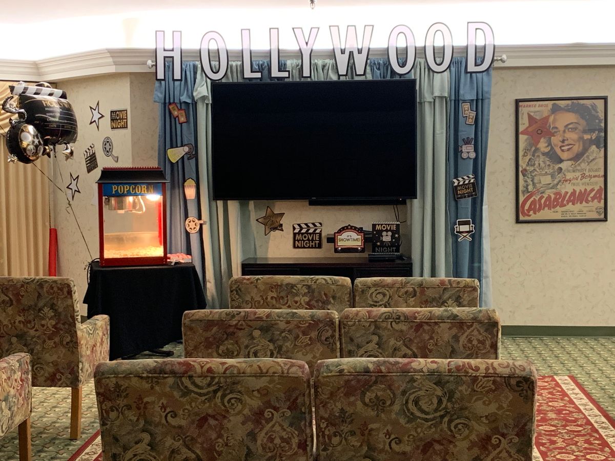 A cozy home theater setup with a Hollywood theme, featuring comfortable seating and a popcorn machine.