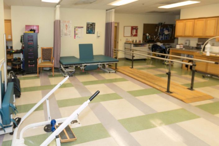 A spacious physical therapy room equipped with parallel bars and exercise equipment, designed for rehabilitation exercises.
