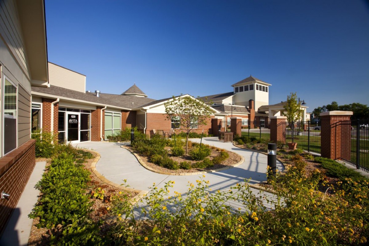A modern building surrounded by landscaped gardens and pathways on a clear day.