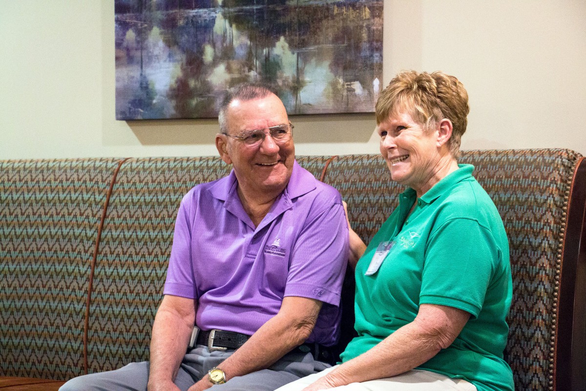 Two people sitting on a couch, smiling and engaging in conversation.