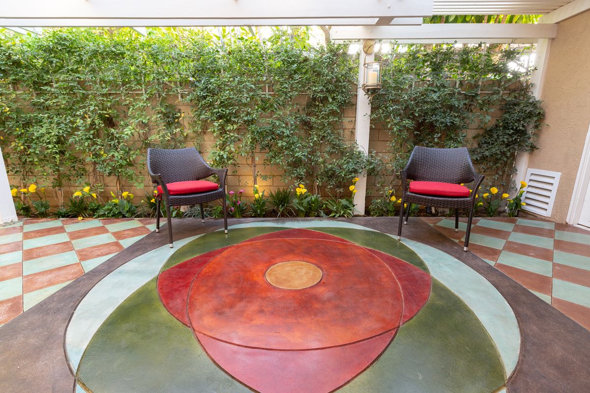 A cozy outdoor patio with two chairs and vibrant greenery.