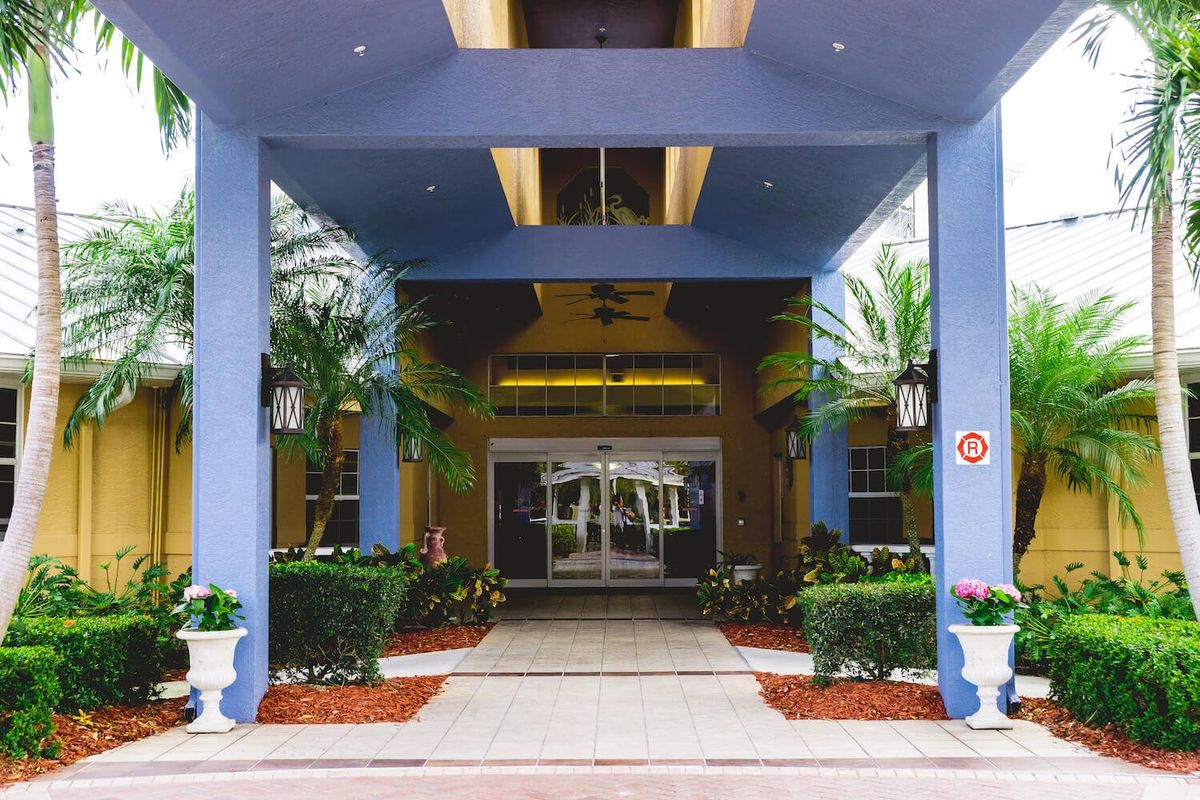A well-maintained hotel entrance with symmetrical landscaping and vibrant colors.