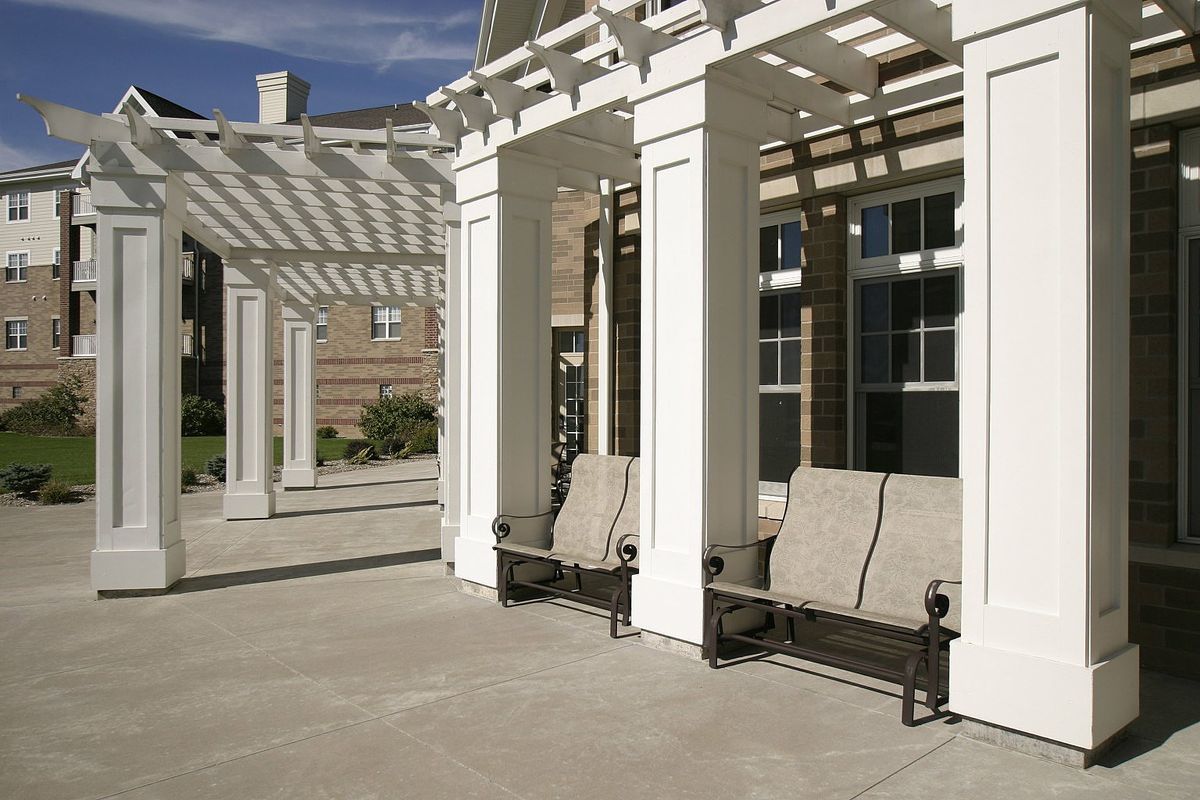 An outdoor area featuring a white pergola with benches underneath, providing a shaded seating space.