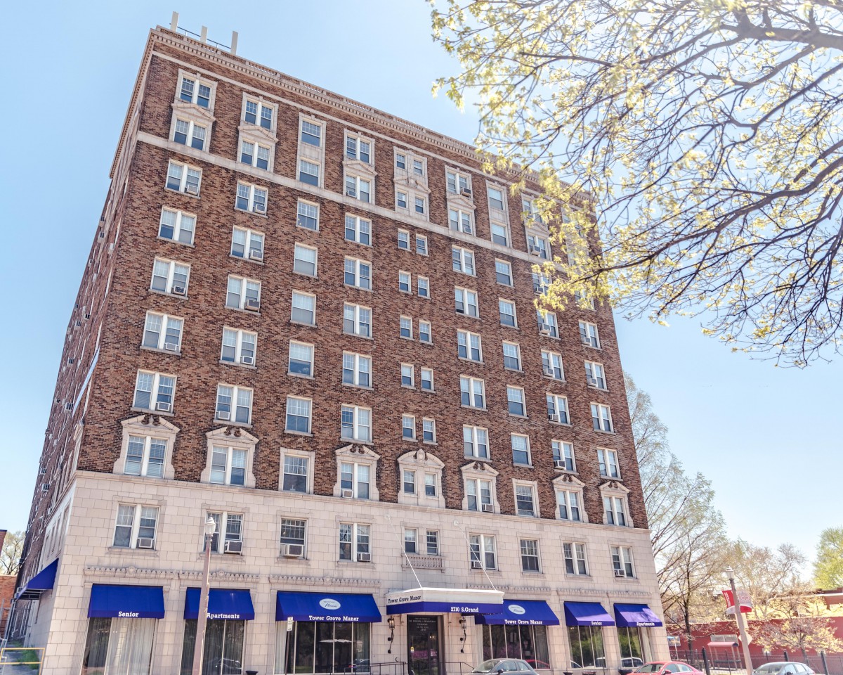 A brick hotel building with blue awnings under a clear sky.