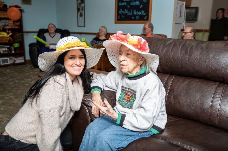 Two people wearing decorative hats, sitting on a couch and smiling.