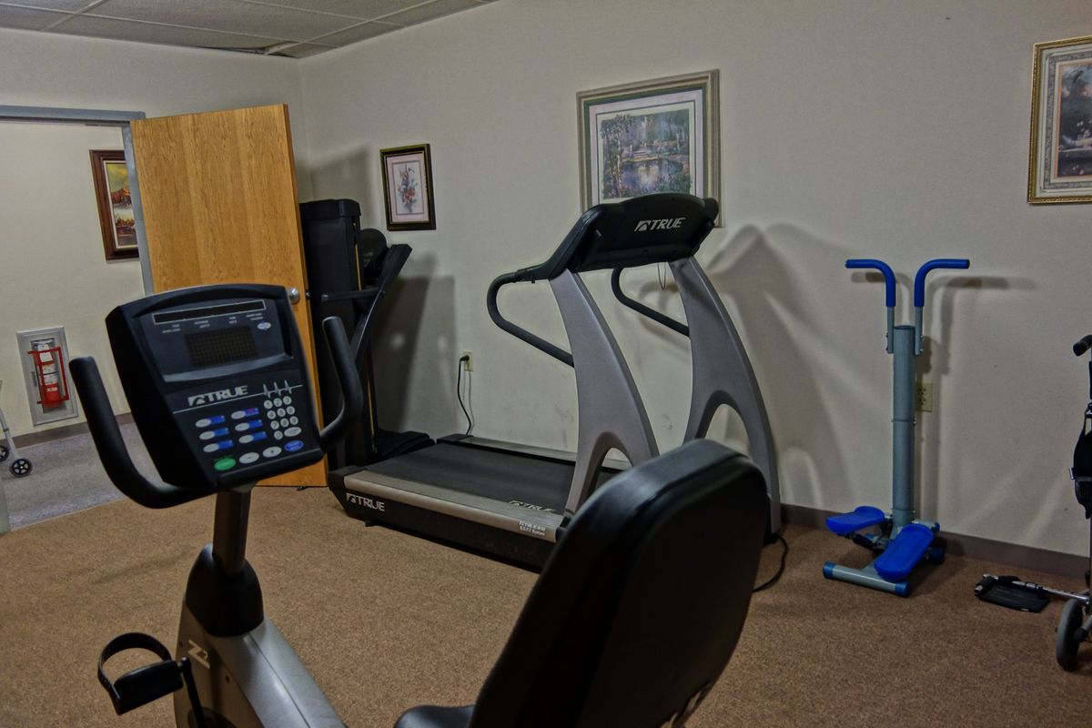 A small gym setup with various exercise equipment including a treadmill and stationary bike.