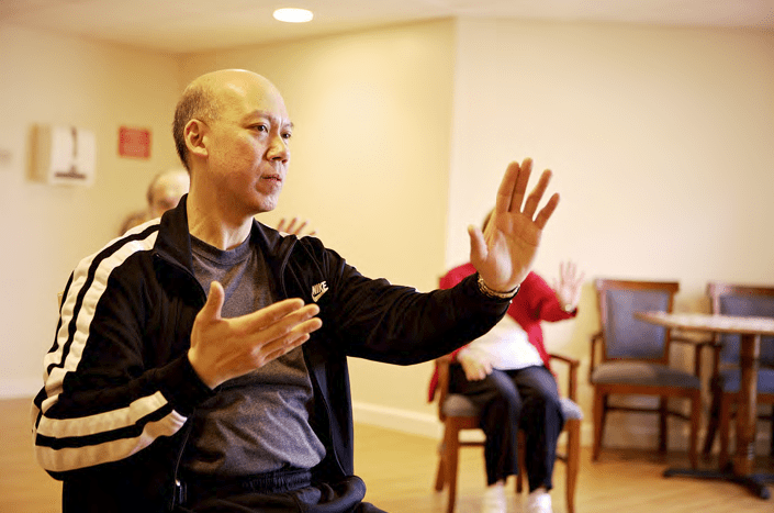 An elderly man practicing Tai Chi indoors, focusing on his movements for relaxation and wellness.