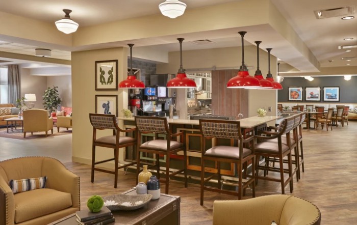 A modern kitchen with a bar area featuring red pendant lights and comfortable seating.