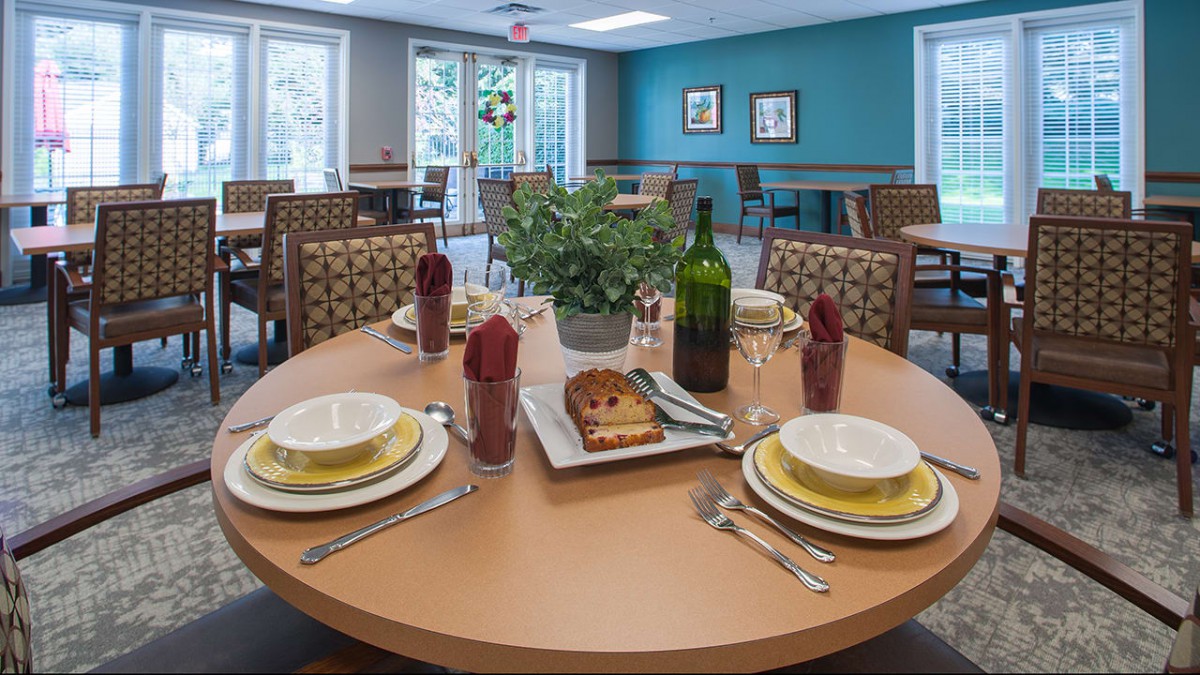 A neatly set dining table with plates, cutlery, and a wine bottle in a cozy dining room.